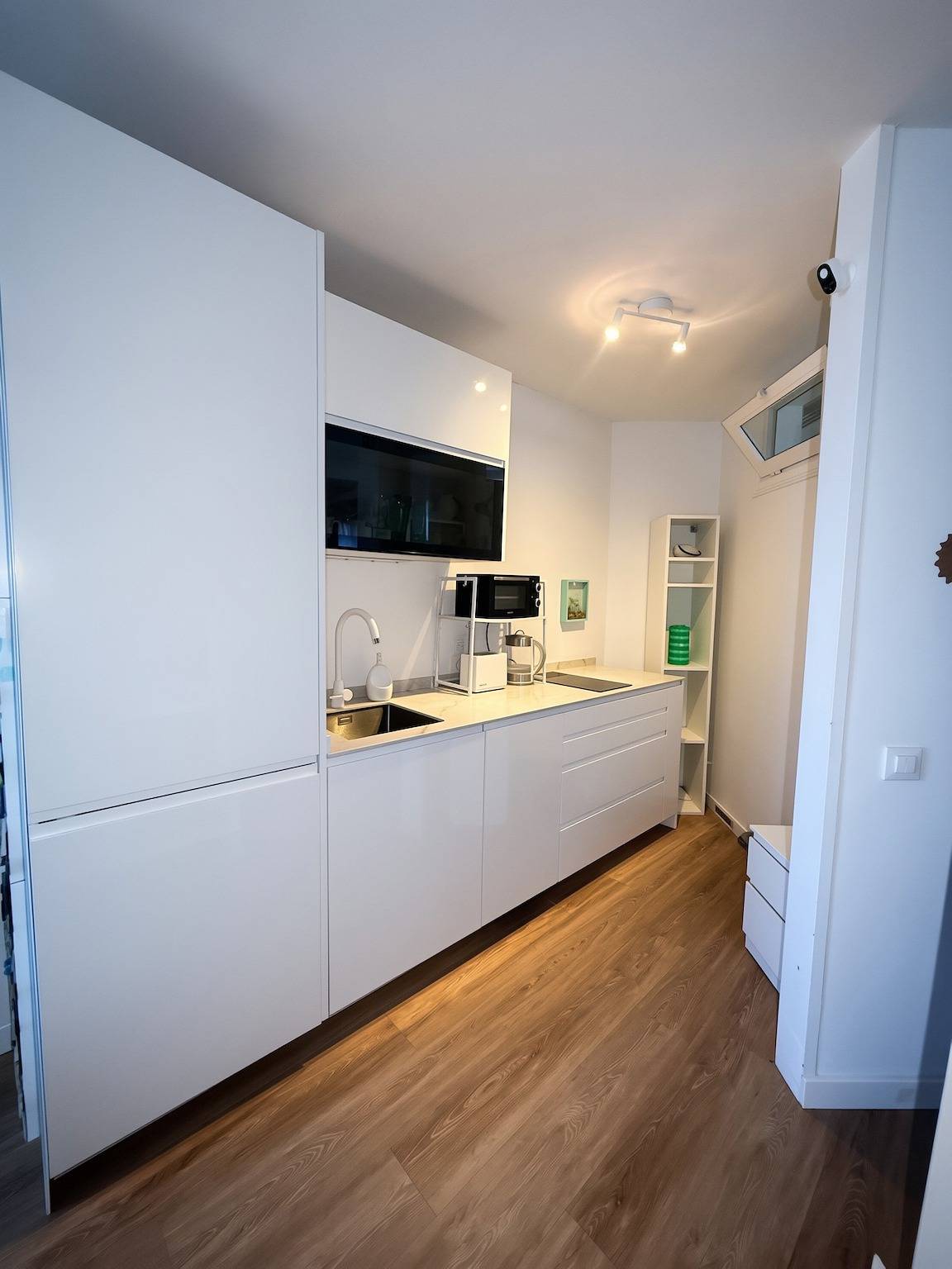 White kitchen with tall cupboards, sink and microwave