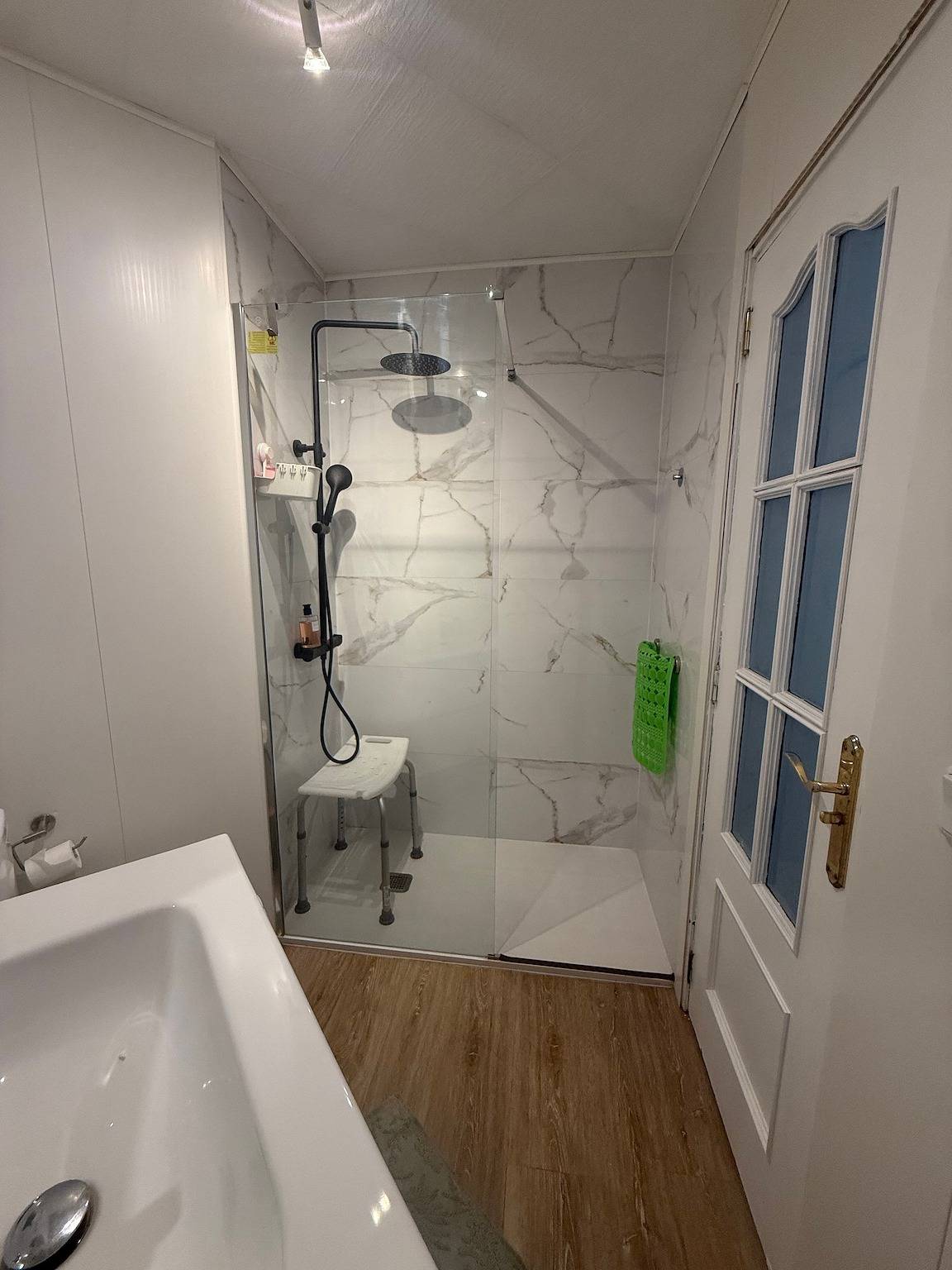Bathroom with walk-in glass shower and a shower stool